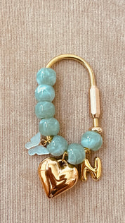 Gold earring with turquoise beads and a heart charm on a beige background