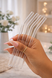 Hand holding four clear straws with a blurred indoor background