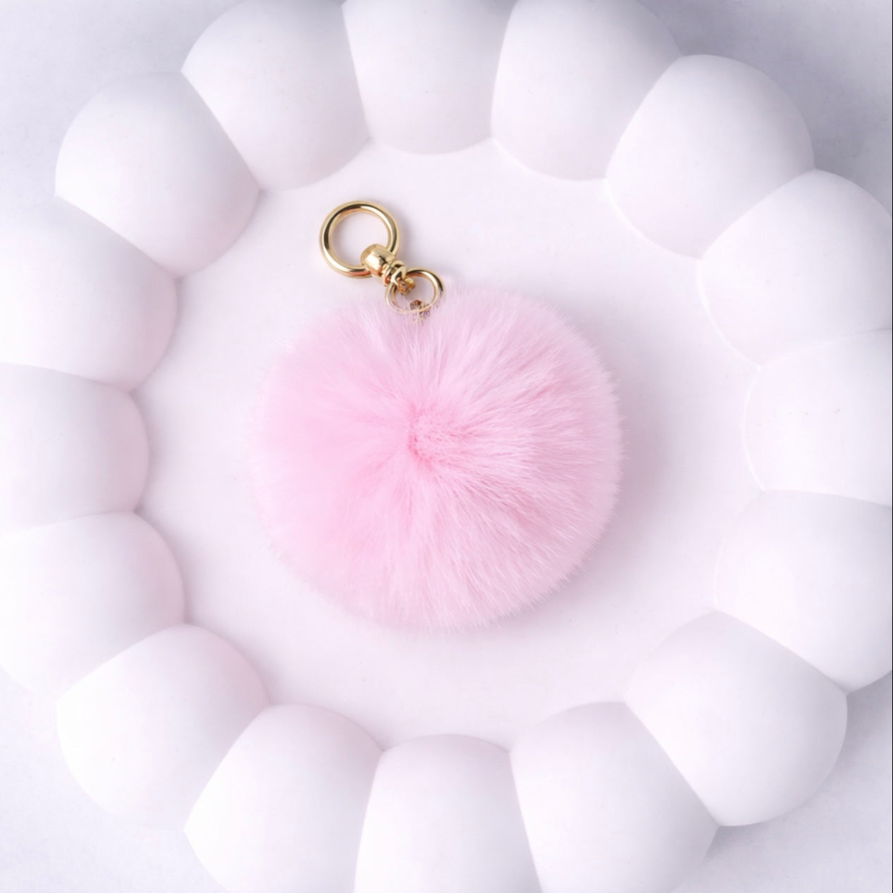 Pink fluffy keychain on a white textured background