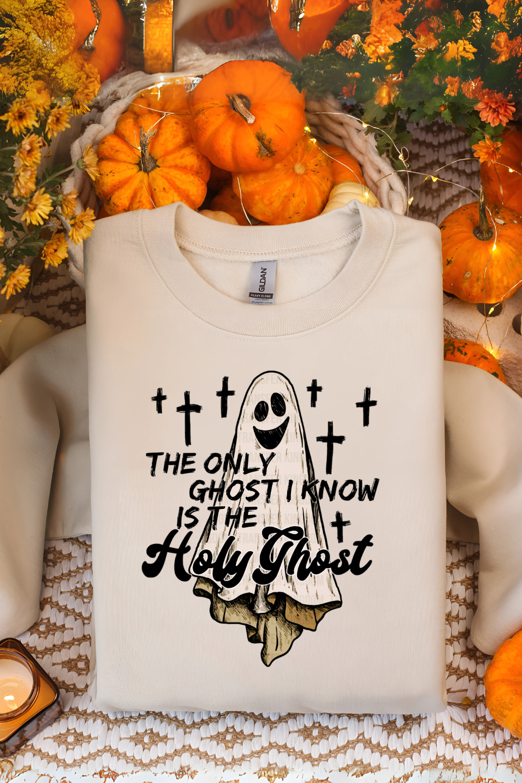 Beige sweatshirt with ghost graphic and text in a Halloween-themed setting with pumpkins and flowers.